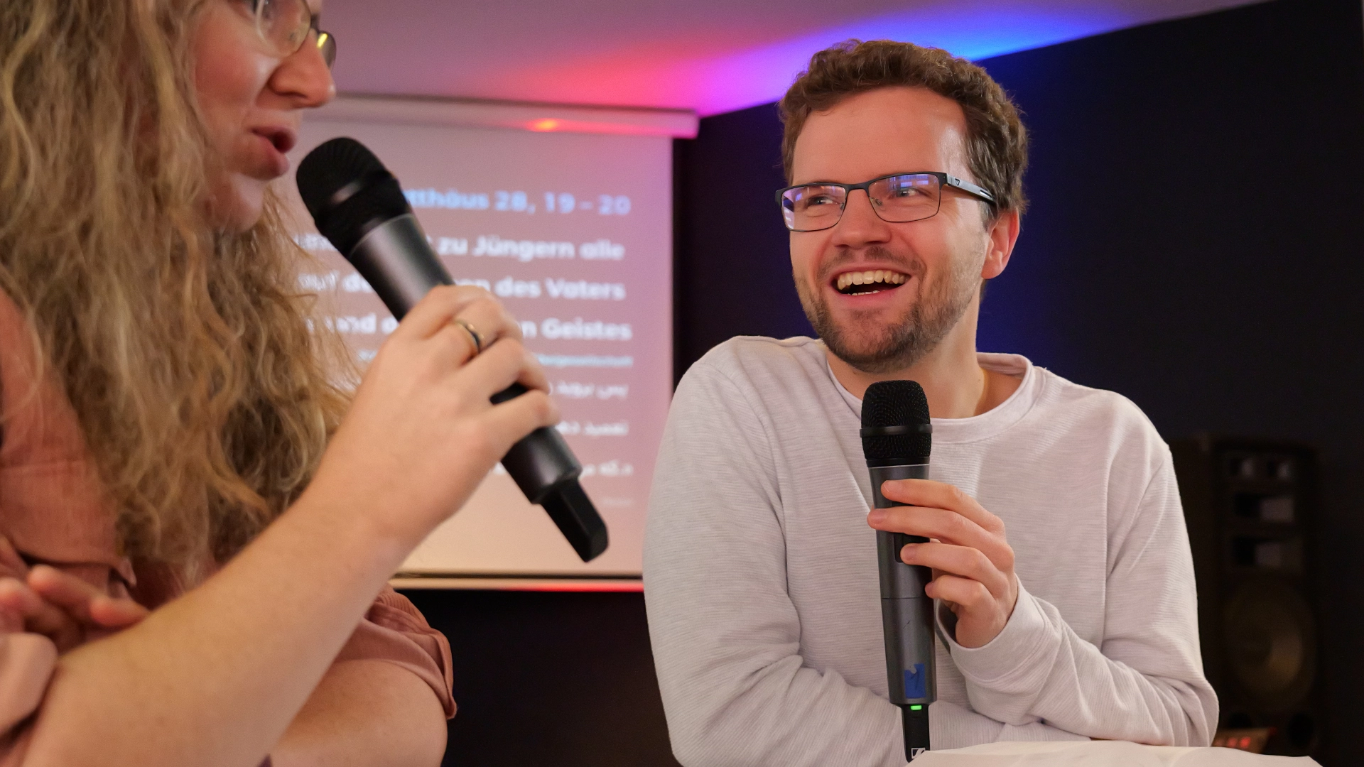 Benjamin Weis, Pastor der Elim Eichsfeld Gemeinde, schaut lächelnd mit einem Mikrofon in der Hand zur einer Person während eines Interviews